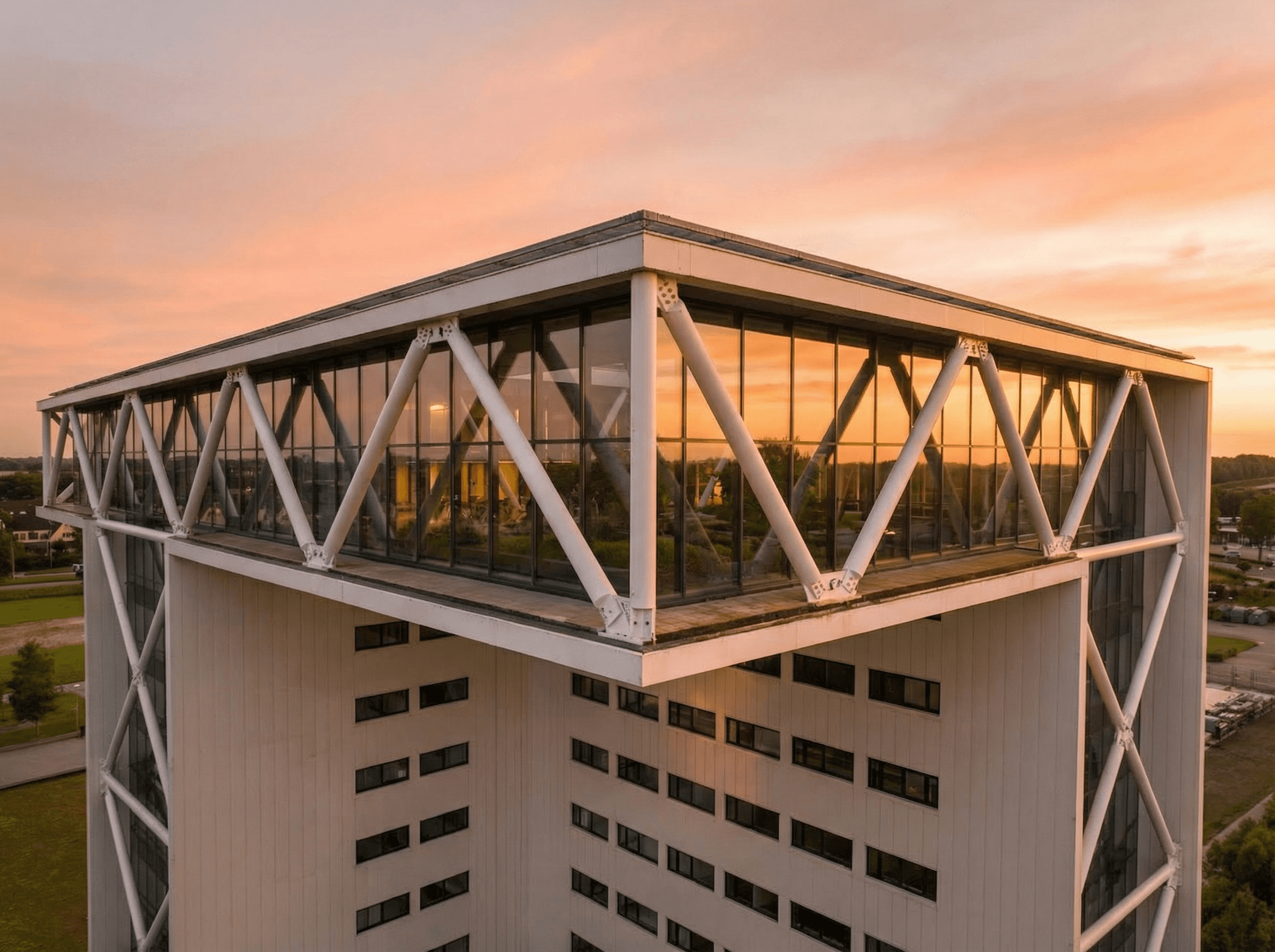 Modern office building with large windows reflecting a vivid orange sunset sky, silhouetted figure visible through the glass.