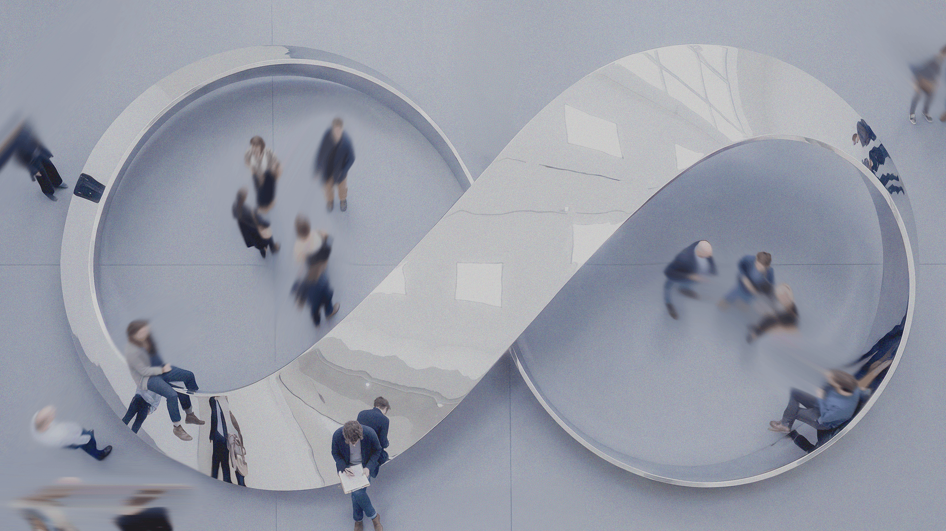 Infinity symbol architectural piece in a minimalist grey setting with people sitting and walking around it.