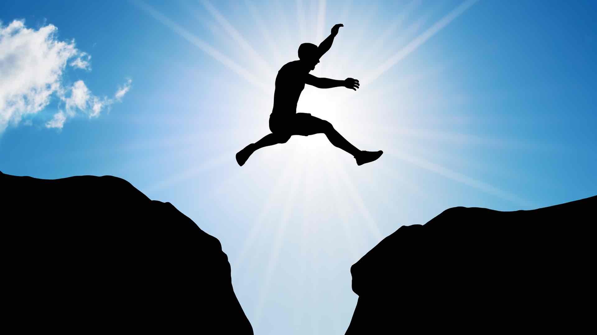 a man jumping from one big rock to another