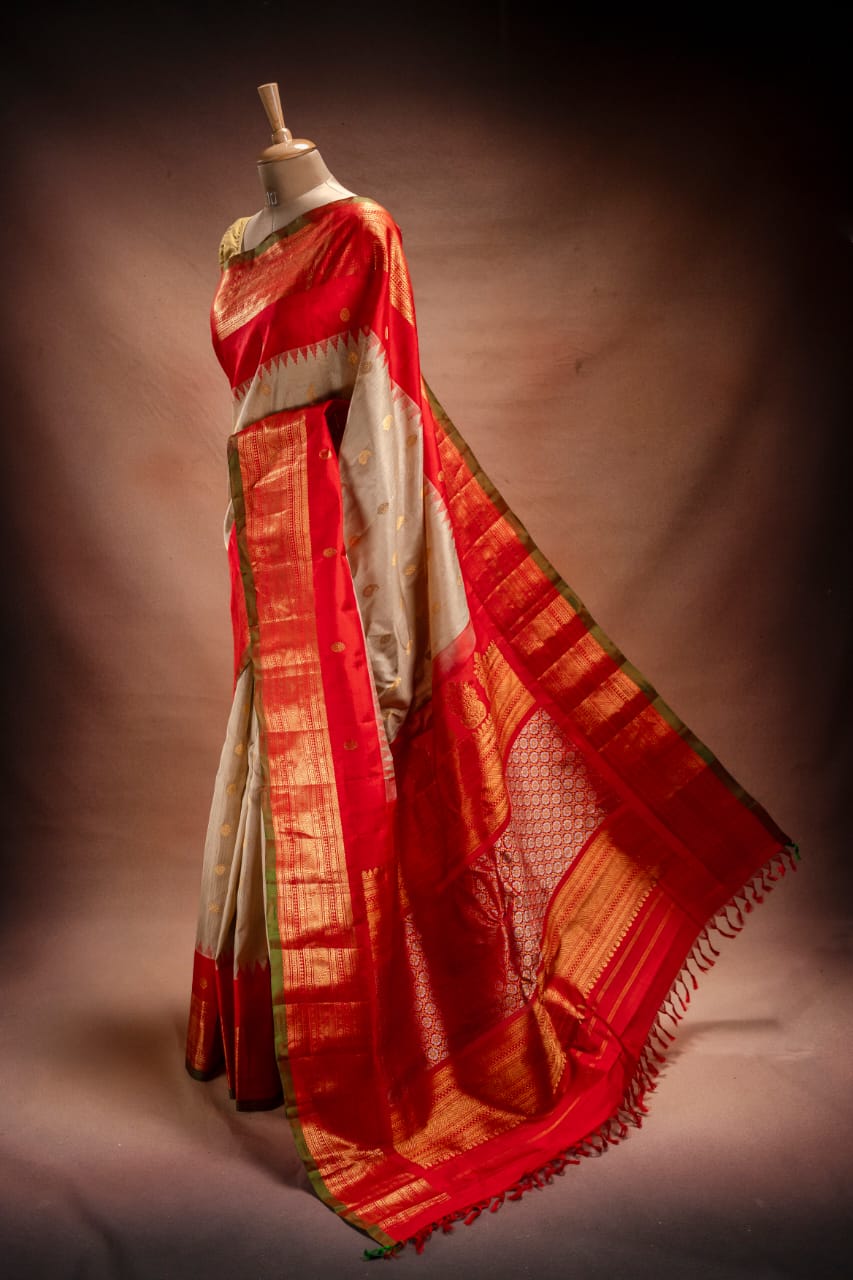 A golden Gadwal saree with rich red borders from That Saree Shop, draped on a mannequin to highlight its intricate zari weaving, silk-cotton texture, and regal South Indian craftsmanship.