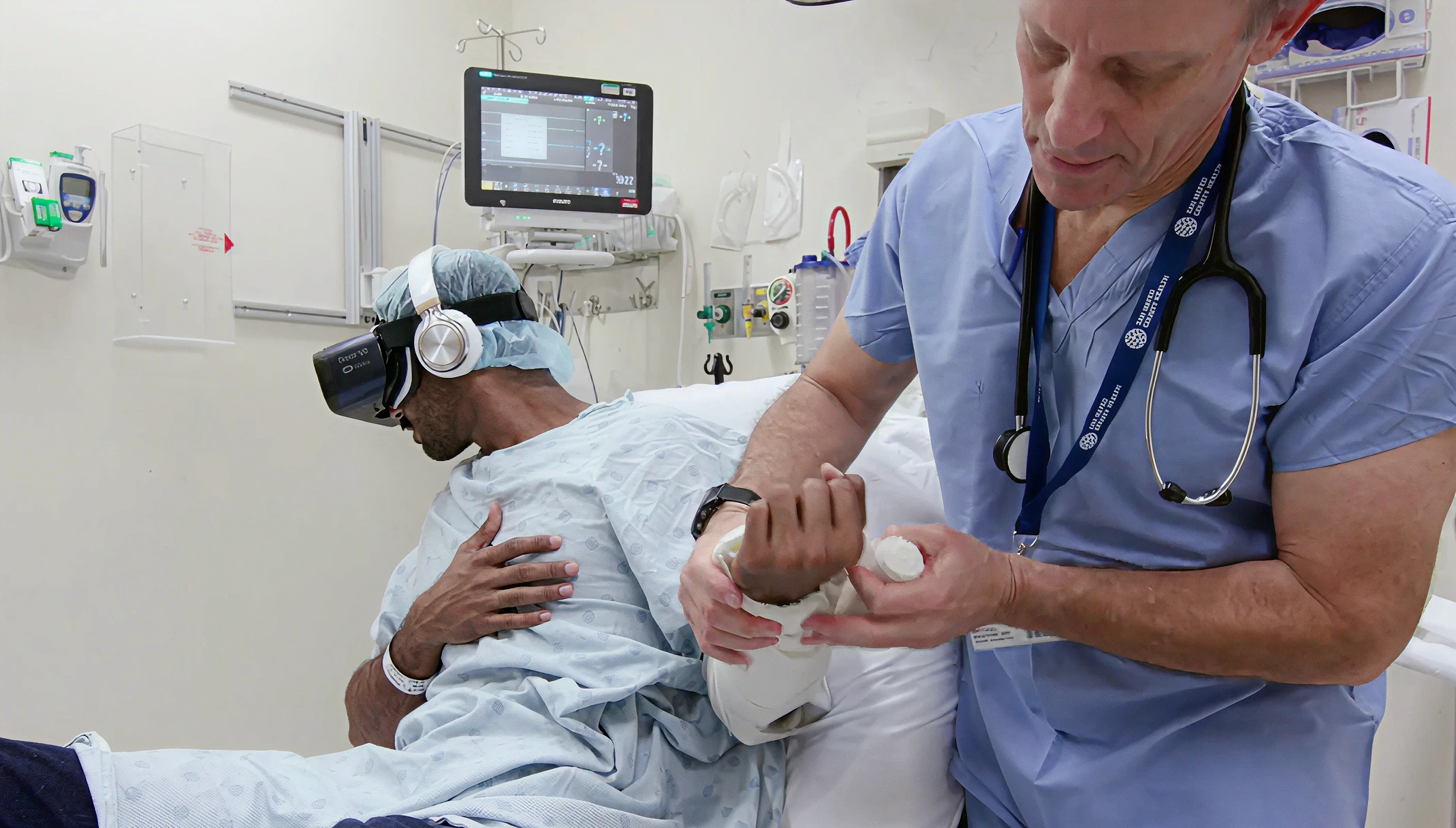 Hospital patient wearing a VR headset in a clinical bed for pain management distraction while a clinician with a stethoscope attends to their arm