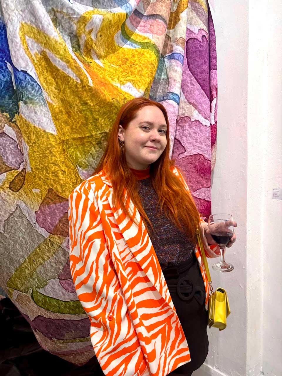 Retrato de Rochi Cuenca, en el marco de la exposición "Demasiado es suficiente" realizada en la Galería de Arte Palermo H, en el microcentro Porteño. El dress code era "demasiado" y la artista luce un saco camp atigrado de colores anaranjados. 