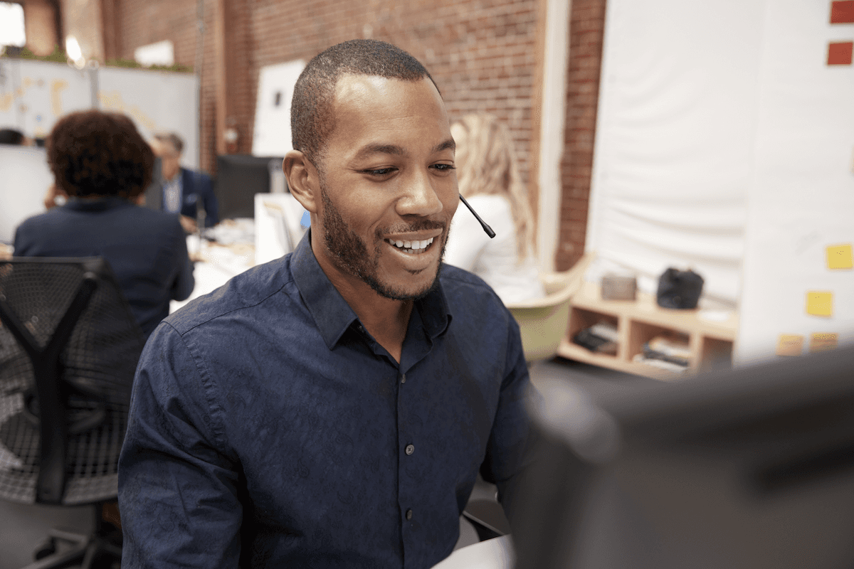 sales enablement app: Smiling man using his computer while on a call