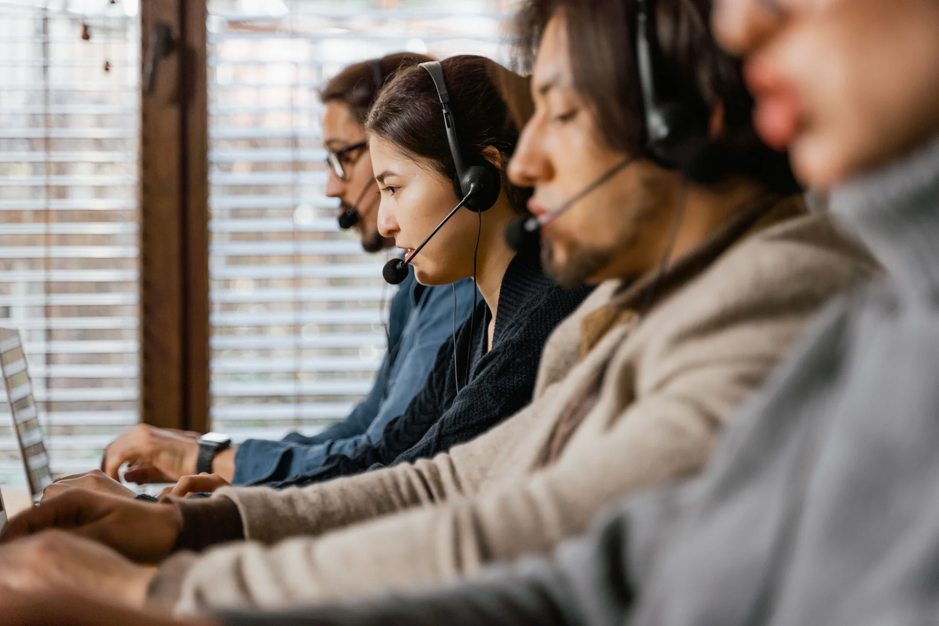 Mitarbeitende mit Headsets führen Telefongespräche am Computer