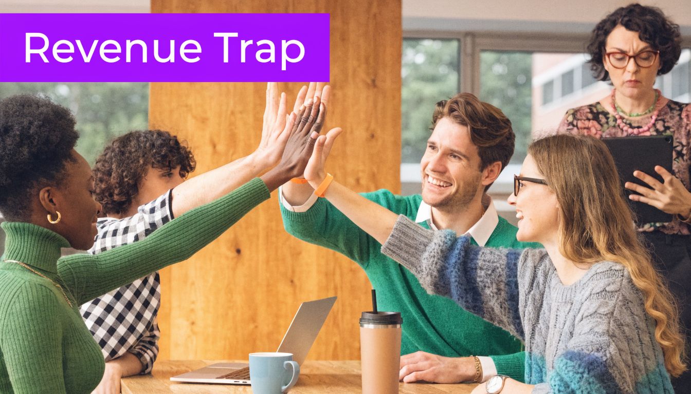 A diverse team of office coworkers high-fiving over a wooden table while celebrating their collective success.