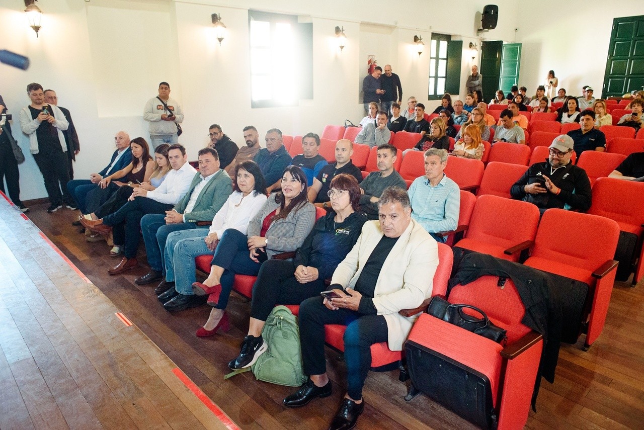 Público sentado en una sala con sillas rojas durante una charla.