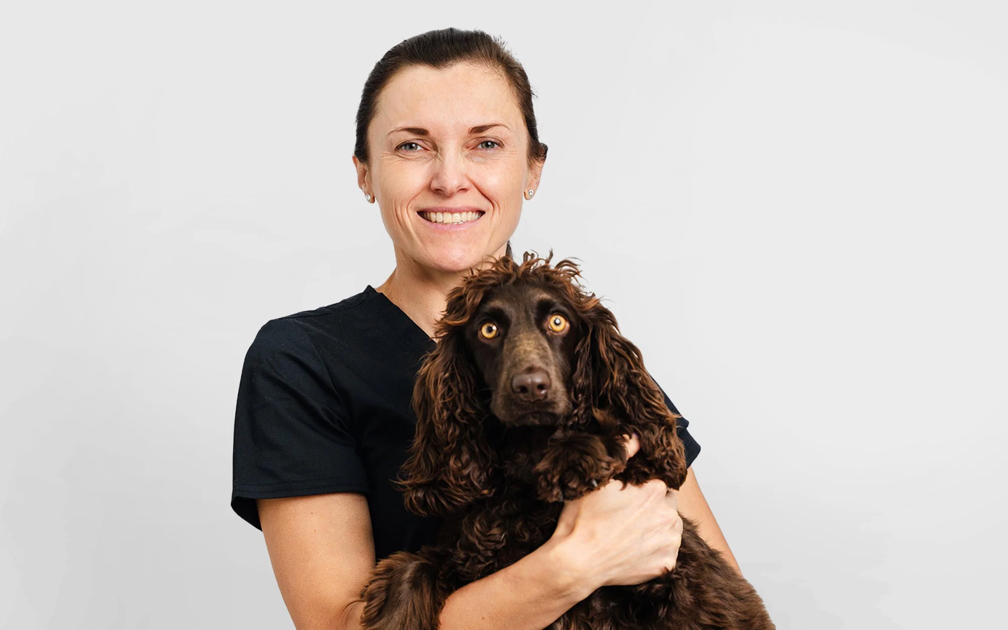 Dr. Paulina Czerska poses with a brown dog at Noble Veterinary Clinic, highlighting the bond between vet and pet.