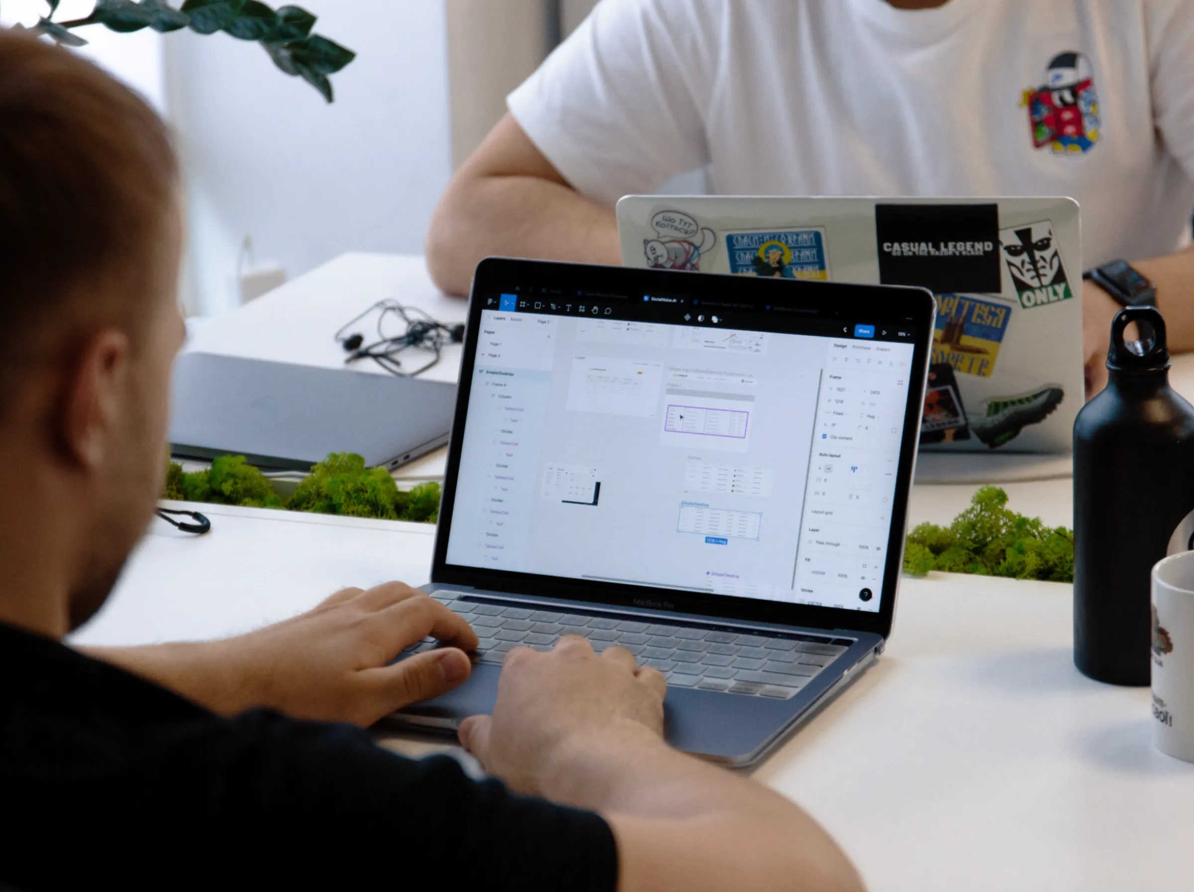 The Fivecube Agency team at work: a UX/UI specialist designing mobile app screens on a MacBook.
