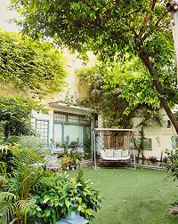Lush private courtyard garden surrounded by mature trees, greenery, and a light-colored home