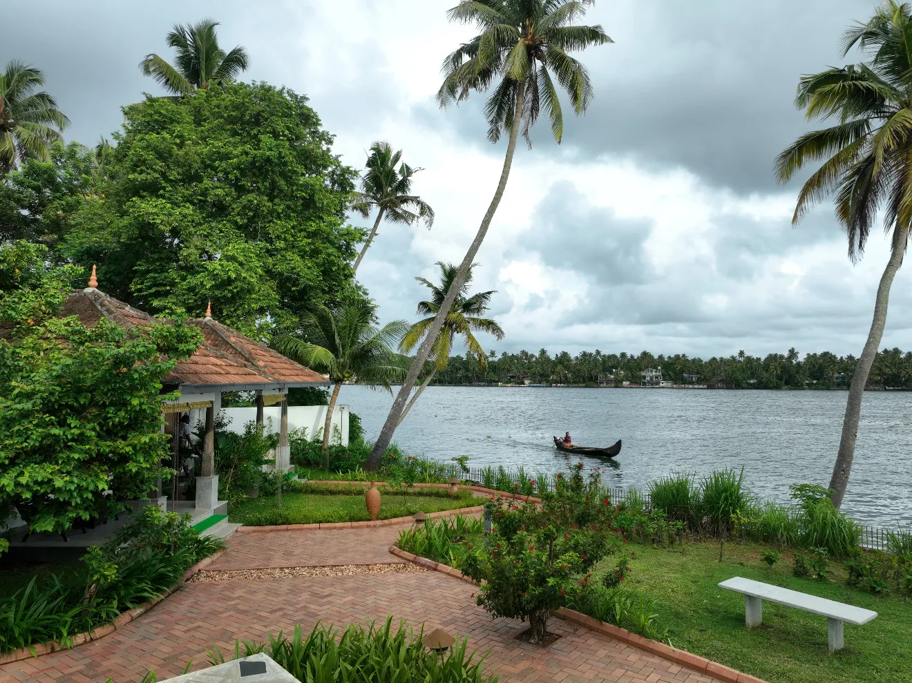 Lake View Villa bathroom at Vedic Village Kodungallur with teal accent wall, oval vessel sink and glass-walled outdoor shower with pebbled flooring