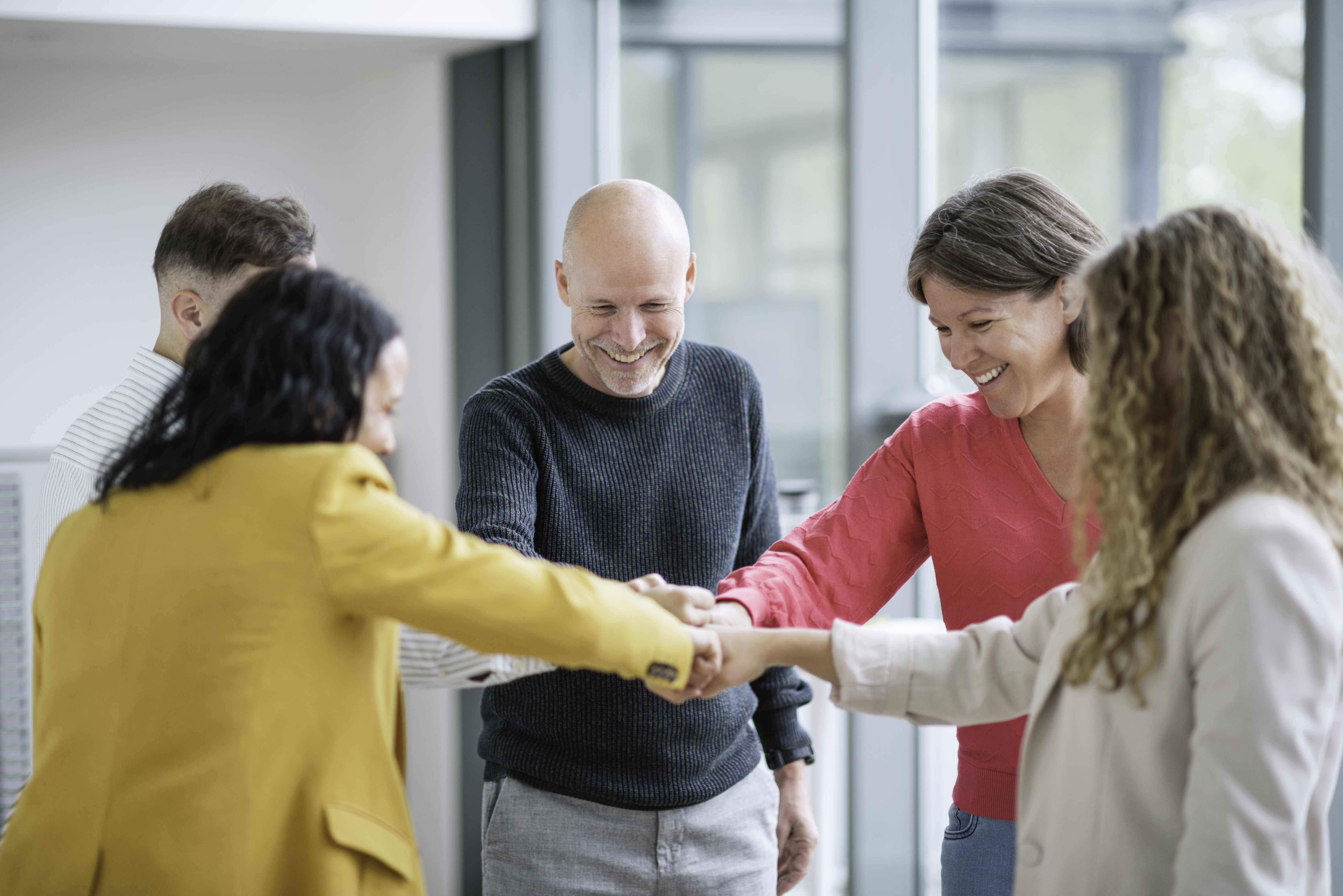 Team members celebrating success together, smiling and joining hands as a symbol of winning together.