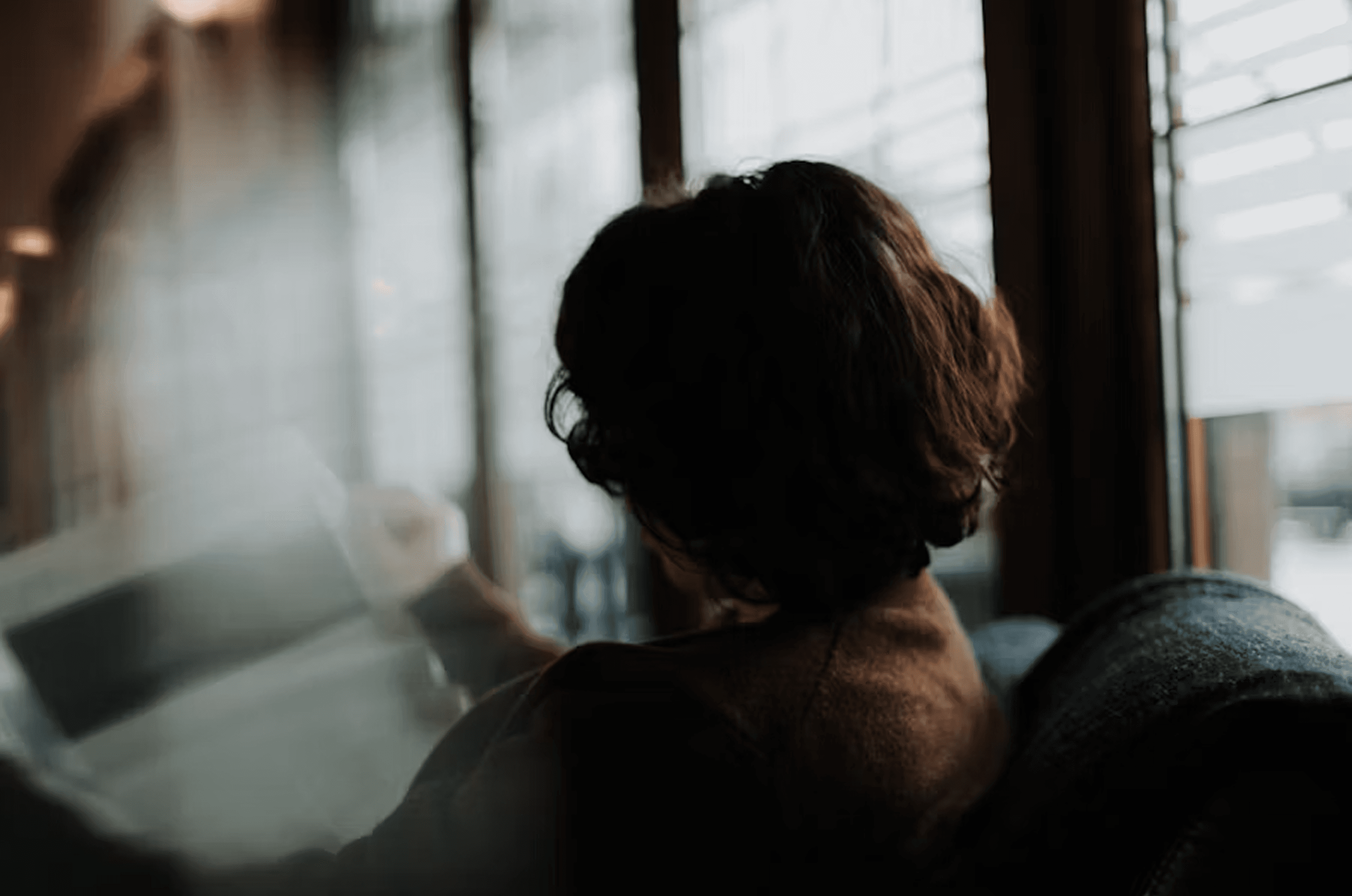 Person sitting by a window working on a laptop in a calm indoor setting, seen from behind — representing focused B2B decision-making, thoughtful LinkedIn marketing, and sustainable SaaS growth aligned with HeySid’s strategic approach.