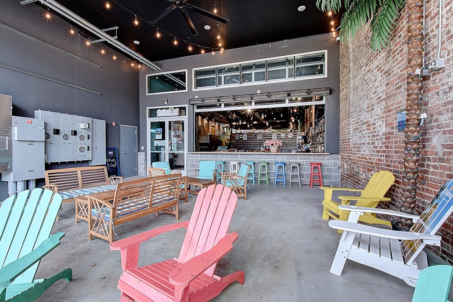 Brightly decorated outdoor seating area with colorful chairs and a cozy seating area, featuring a welcoming bar in the background.