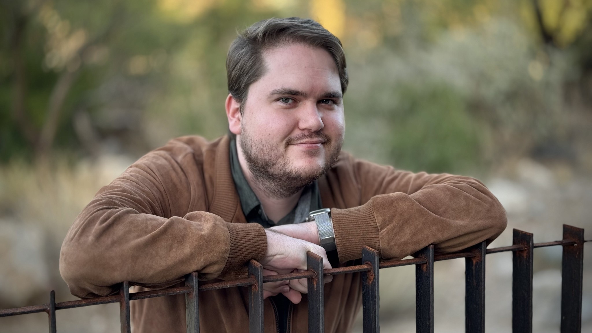 Alex smiling in a brown suede jacket.