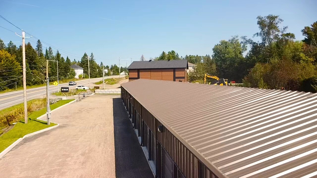 Vue extérieur prise à partir du bout du bâtiment montrant le toit et les portes des minis entrepôts