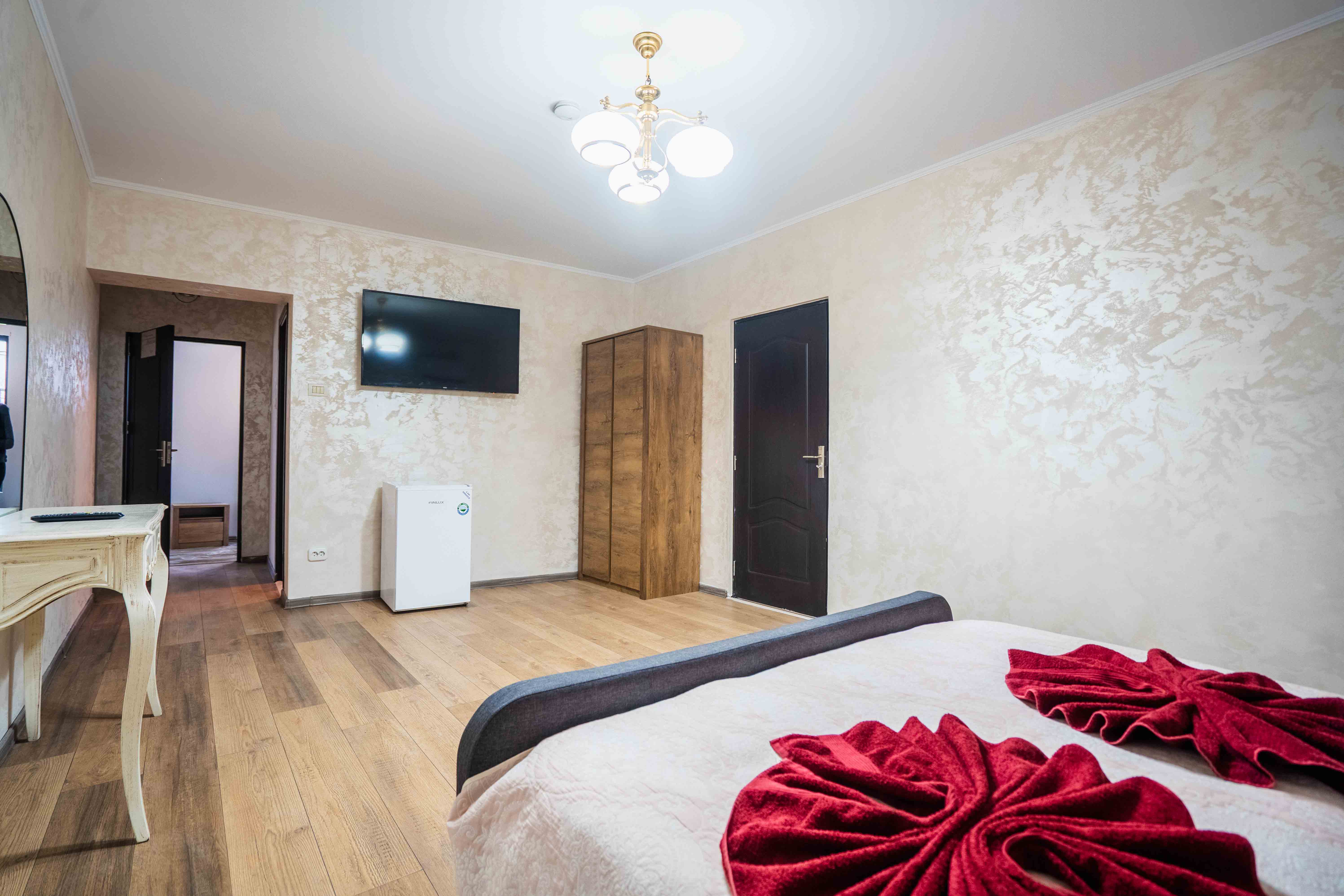A modern house with large windows and a flat roof, surrounded by greenery against a clear blue sky.