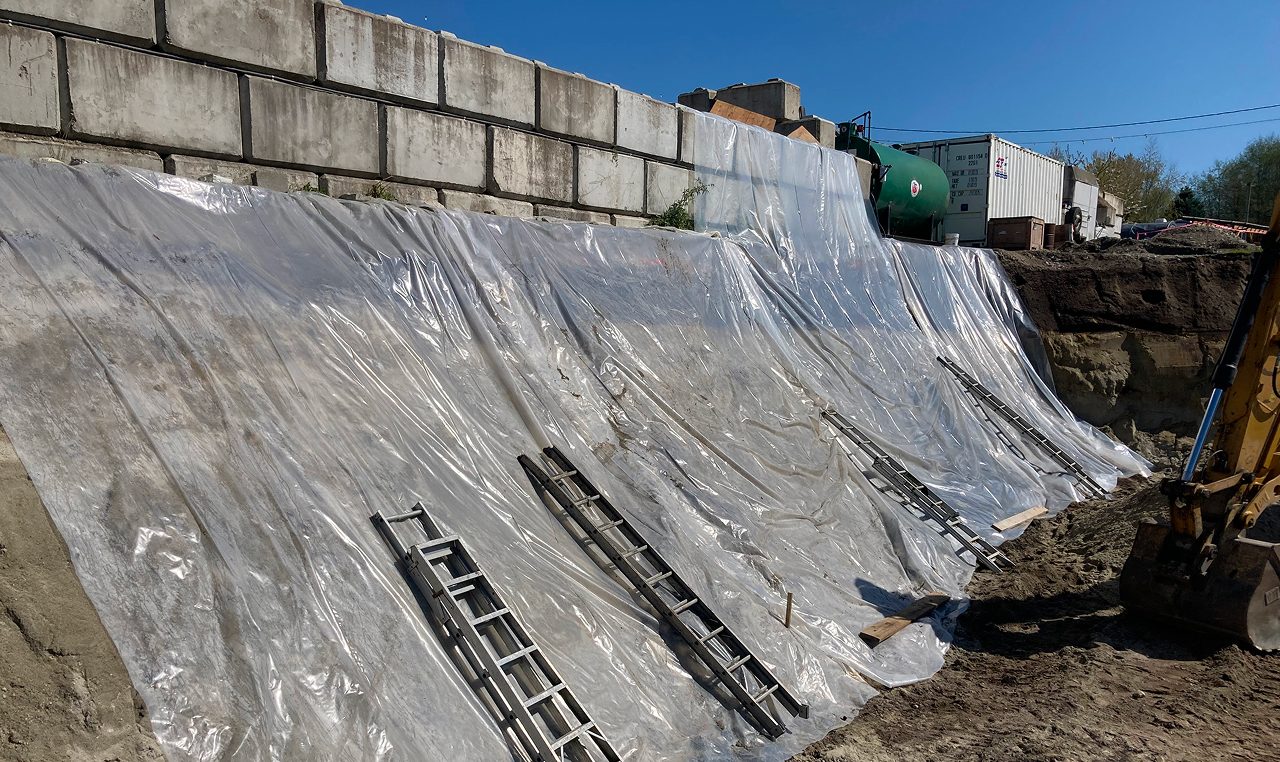 Geogrid reinforcement installation behind lock block retaining wall during construction at Salish Soils