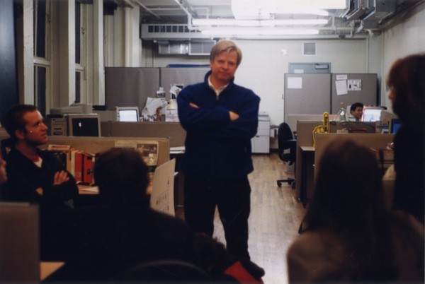 A photo of a person giving a lecture to a group of students while sitting in a classroom.