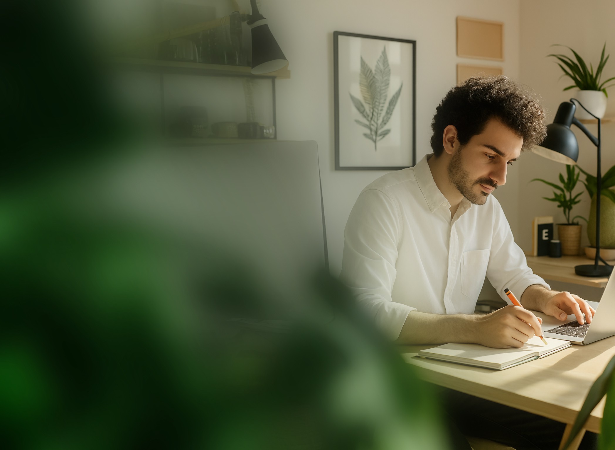 Man sitting at desk on computer taking notes
