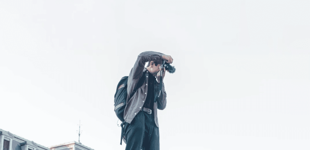 Photo du journaliste Thibaud Mabut en train de filmer avec une caméra, debout contre un ciel dégagé.