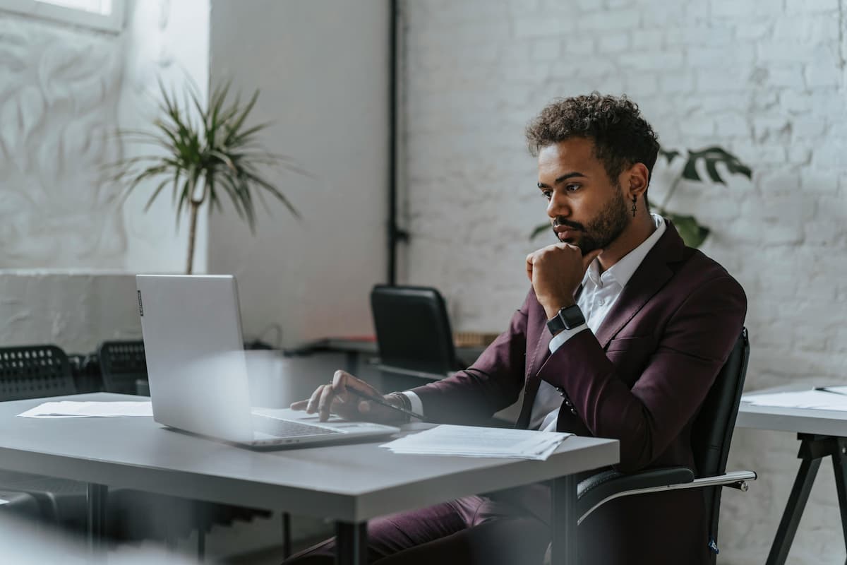 Homem trabalhando no laptop em escritório moderno, analisando dados e planejamento estratégico, representando as vantagens de franquia para empreendedores.