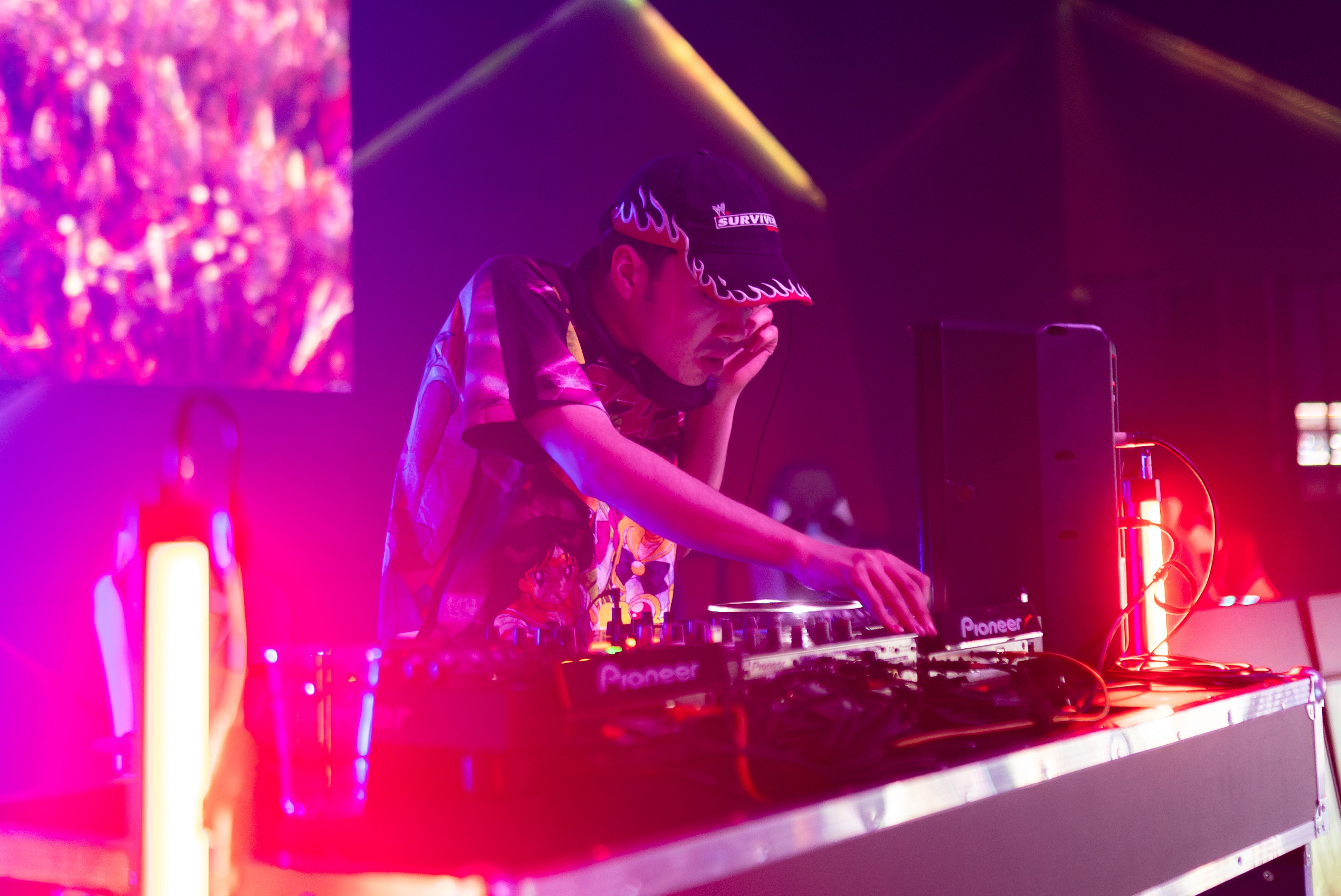 low angle shot of a DJ with red lighting as he turns dial