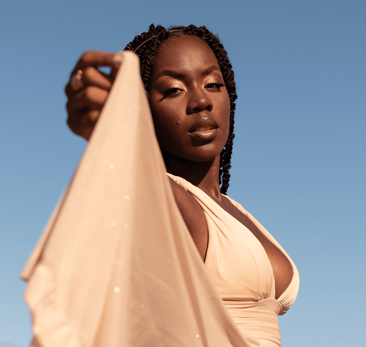 Portrait of a Black woman with gold eyeshadow and a flowing peach fabric