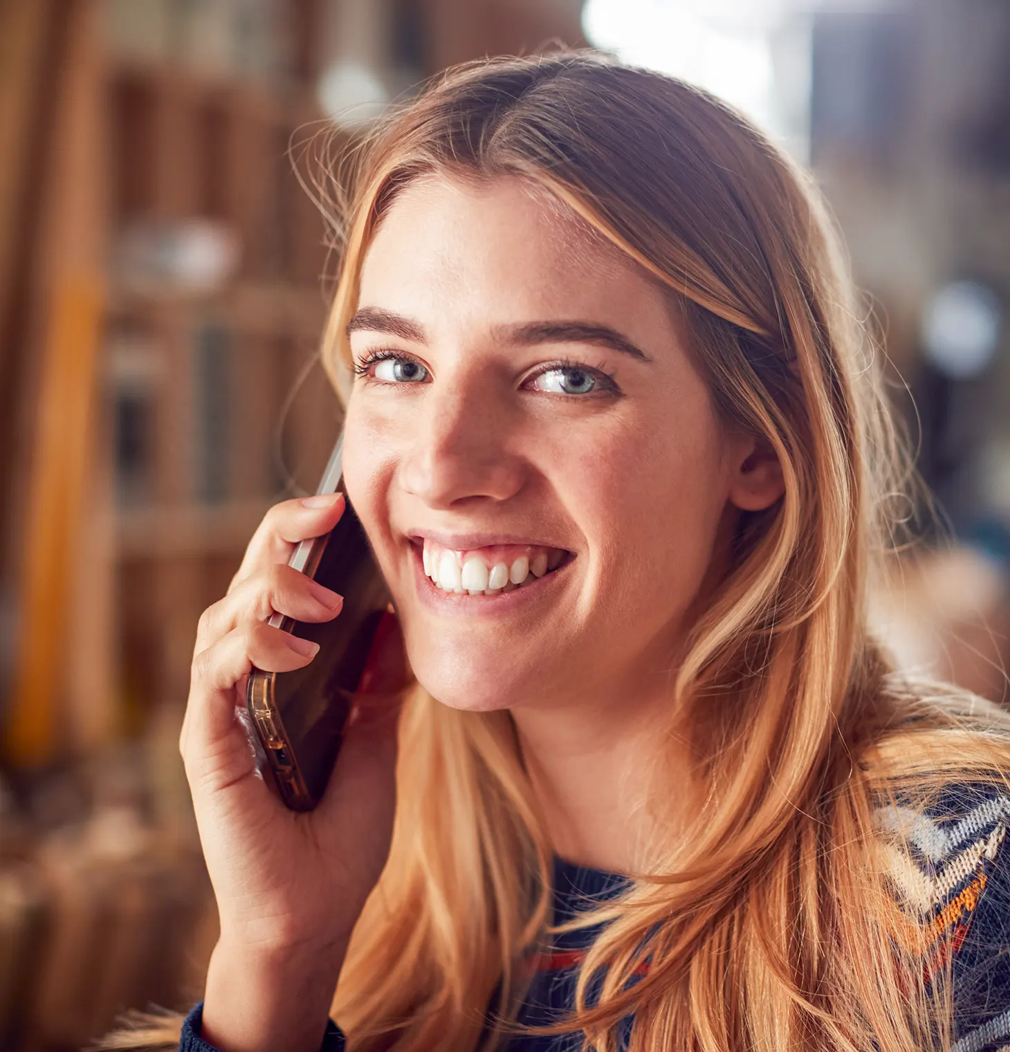 Bilde av en glad kvinne som snakker i en mobiltelefon.