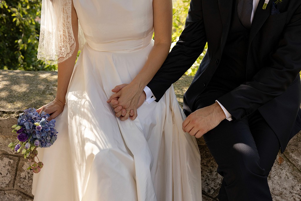 Married couple holsing hands and sitting on a wall