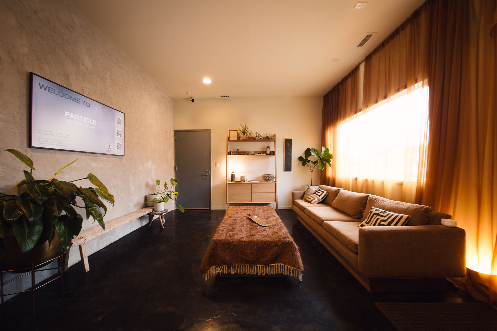 The Particle Studio Lobby stands clean and ready to hosts a booking. A couch and coffee table are positioned by some beautifal decorations.
