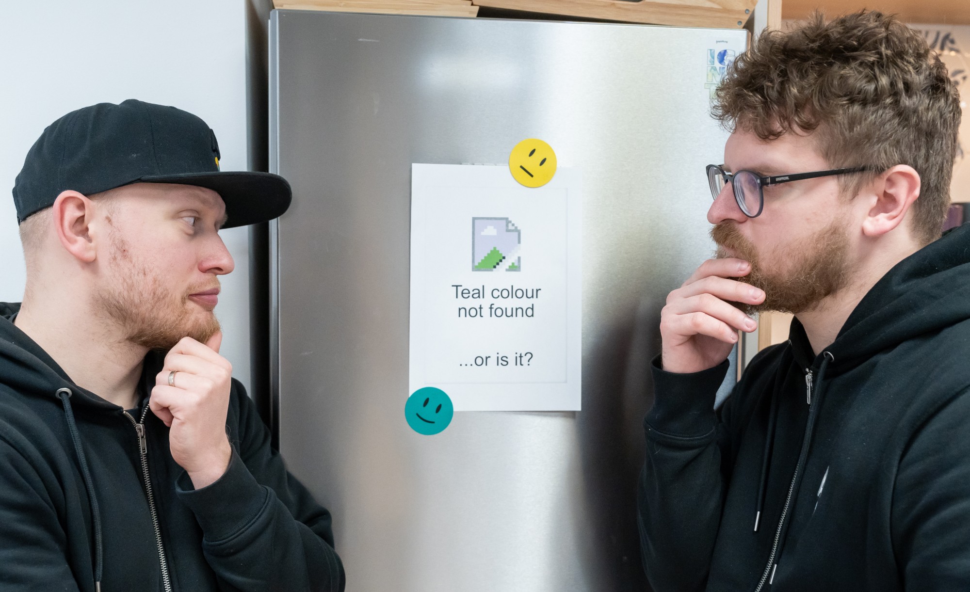The founders looking pensively at a sign on a refrigerator that reads 'Teal colour not found... or is it?