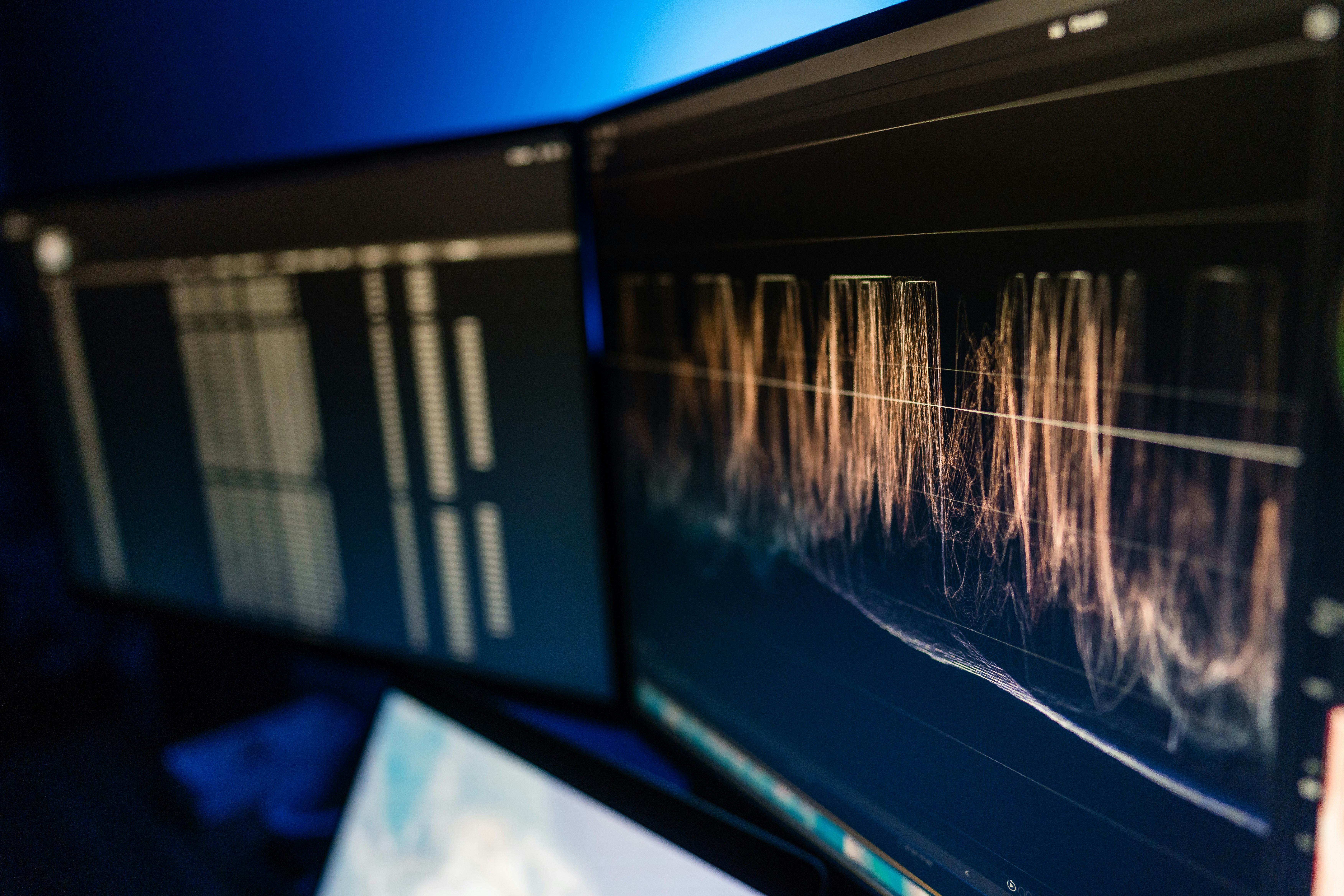 Close-up portrait of a person wearing a gray insulated hooded jacket with the hood up, showing their face framed by the hood against a light background.