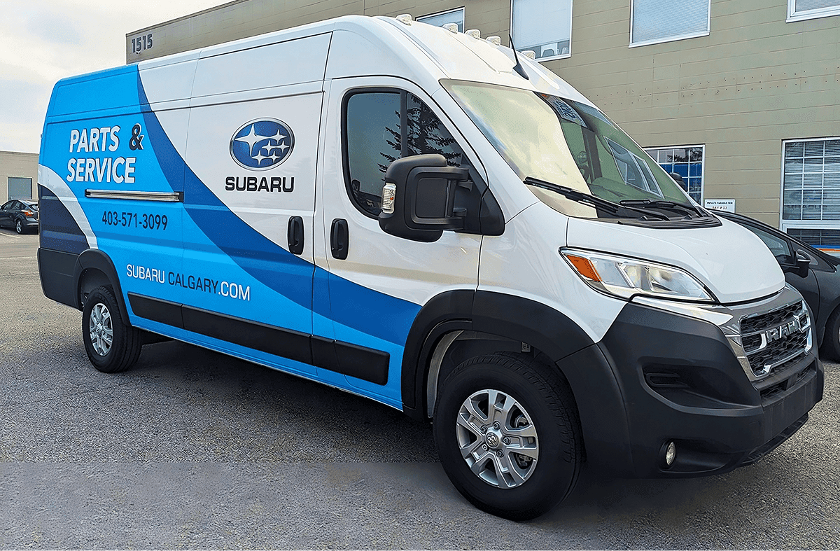dodge windowless white van with white and blue vinyl graphics for Subaru, front-right view
