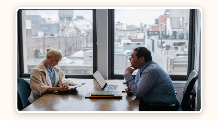 Two professionals discussing documents and laptops
