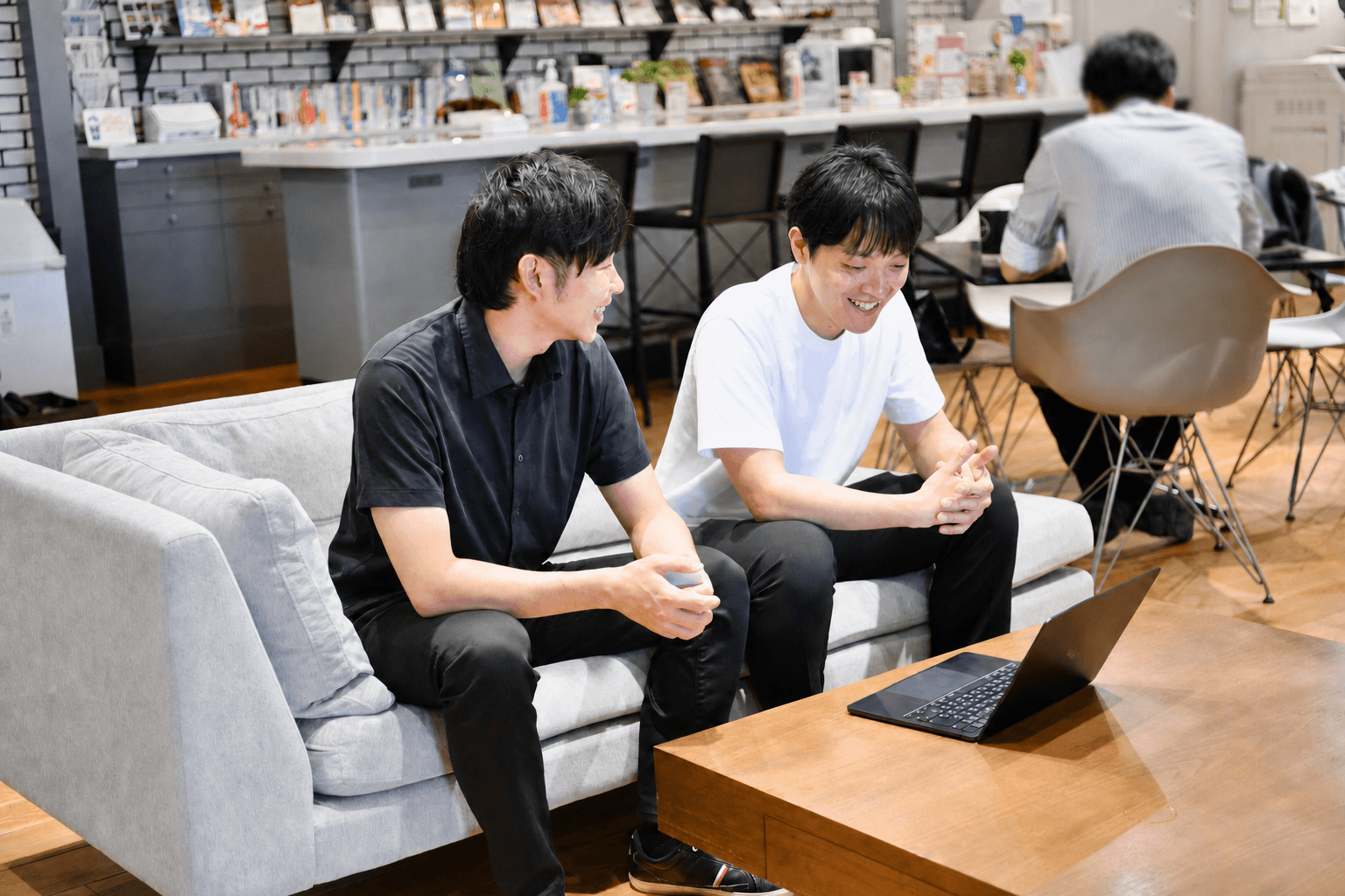 LeapWellメンバーがオフィスのソファでノートPCを見ながら対話する様子
