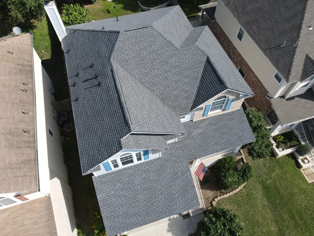 Completed Pewter Grey GAF Timberline HDZ roof on a San Marcos home with blue shutters, 2024.