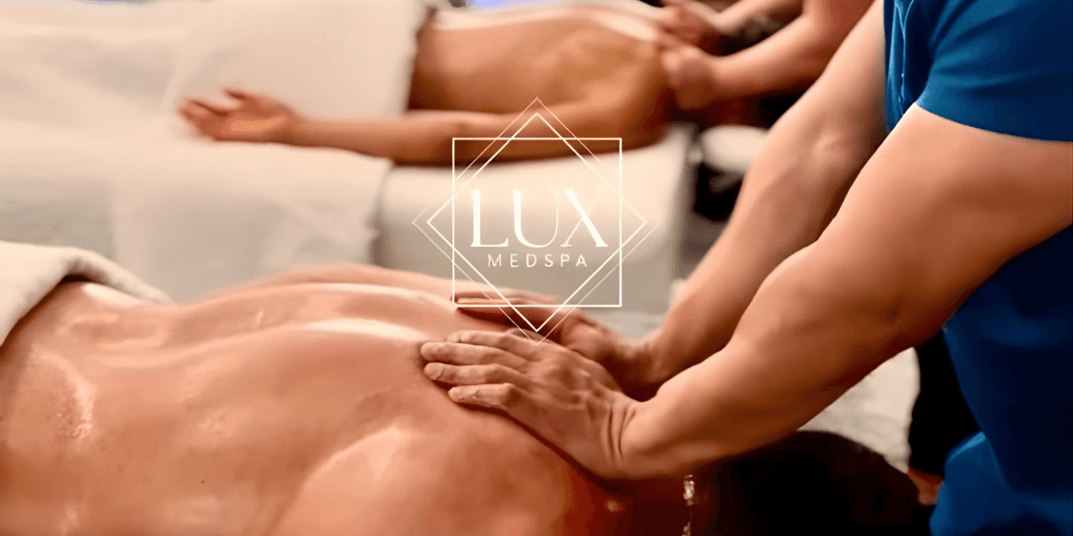 Massage therapist performing back treatment on client in calming spa setting with Lux MedSpa branding visible.