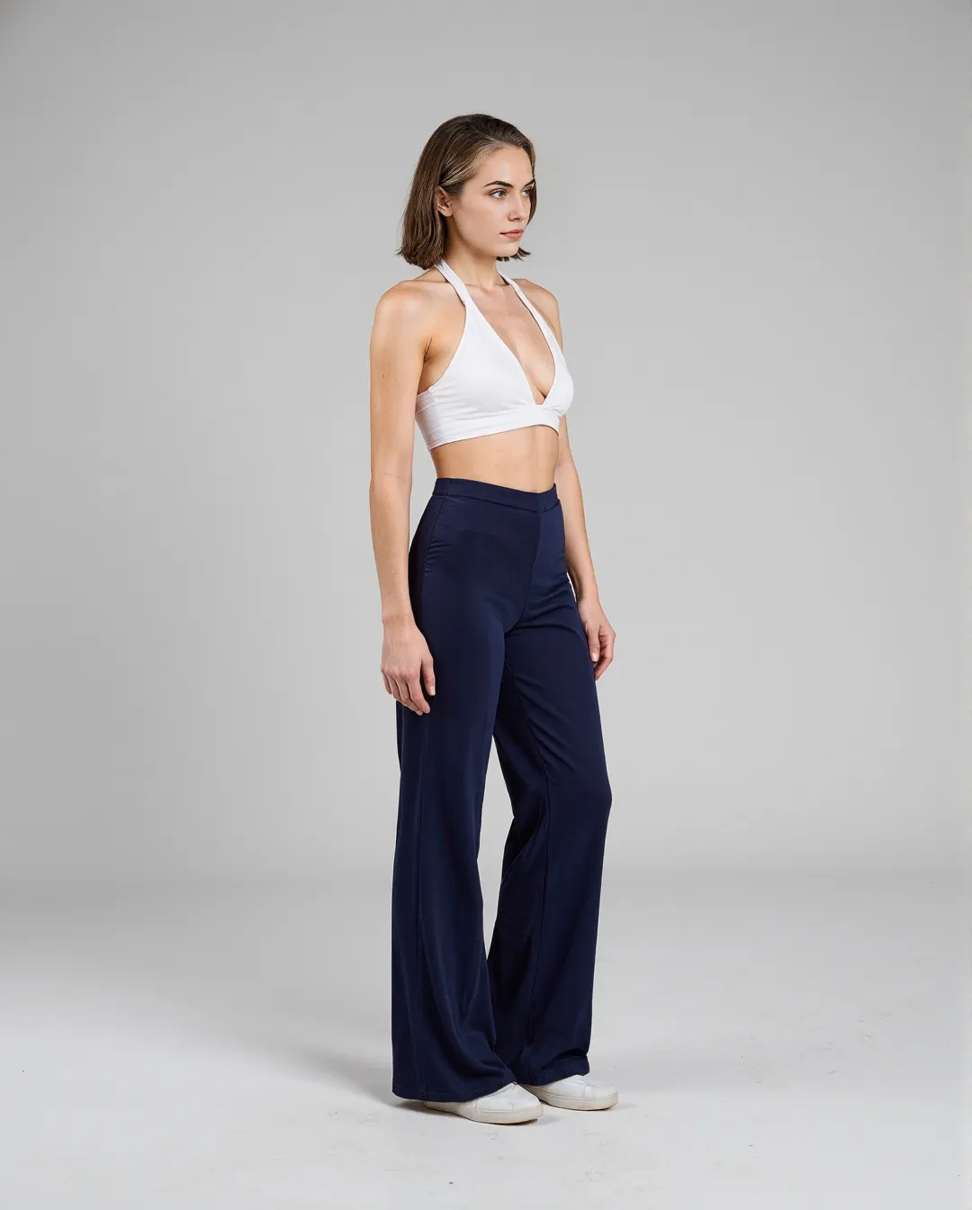 Minimalist fashion photography featuring white halter crop top and navy wide-leg pants against neutral background