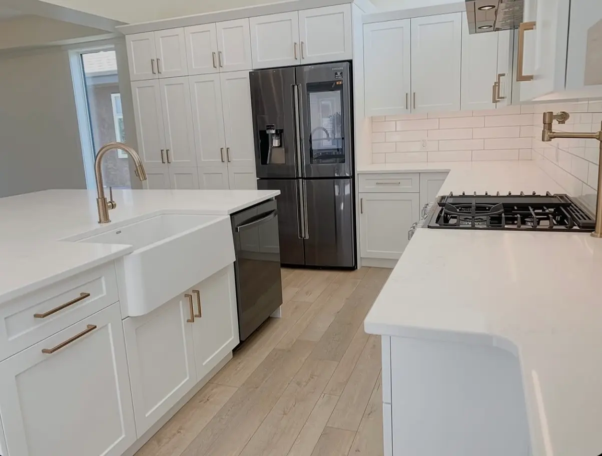 A bright, floor-to-ceiling kitchen deep clean featuring spotless white cabinets, polished quartz countertops, and a clean wood-style floor, showing a complete top-to-bottom move-out service.