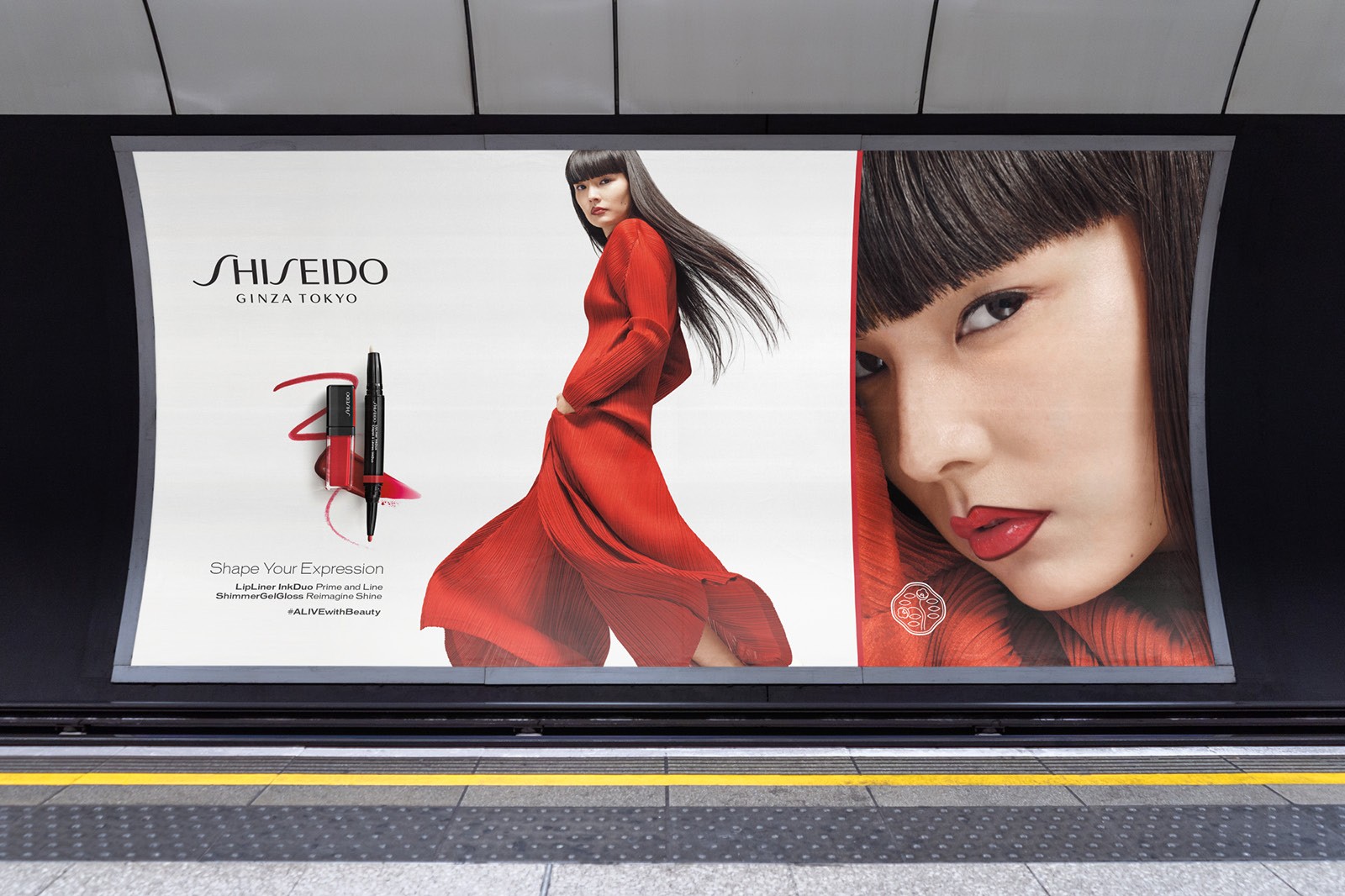Advertisement featuring a model in a red dress and a close-up of her face, displayed in a subway station.