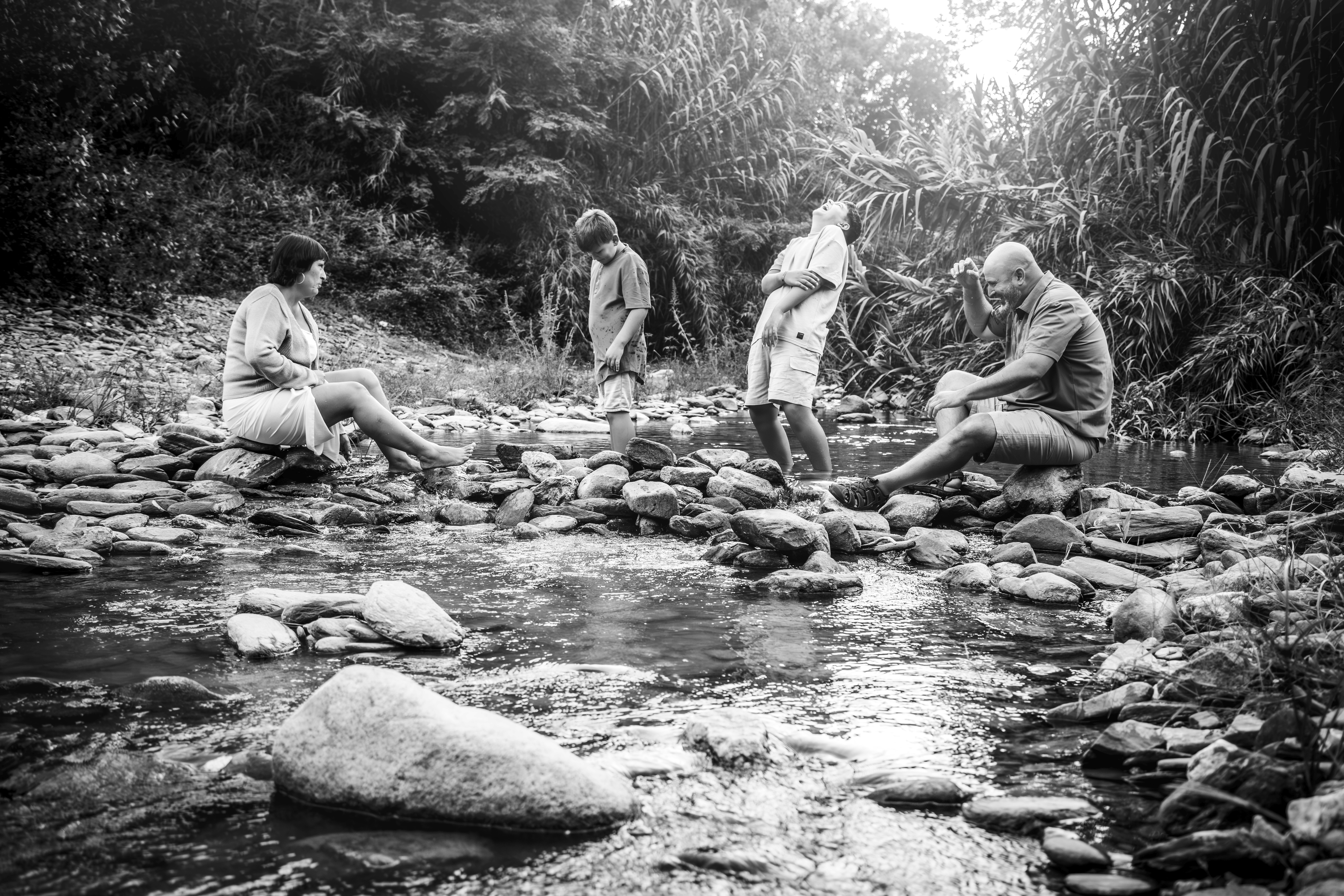 Familia en un río sentados riendose en blanco y negro