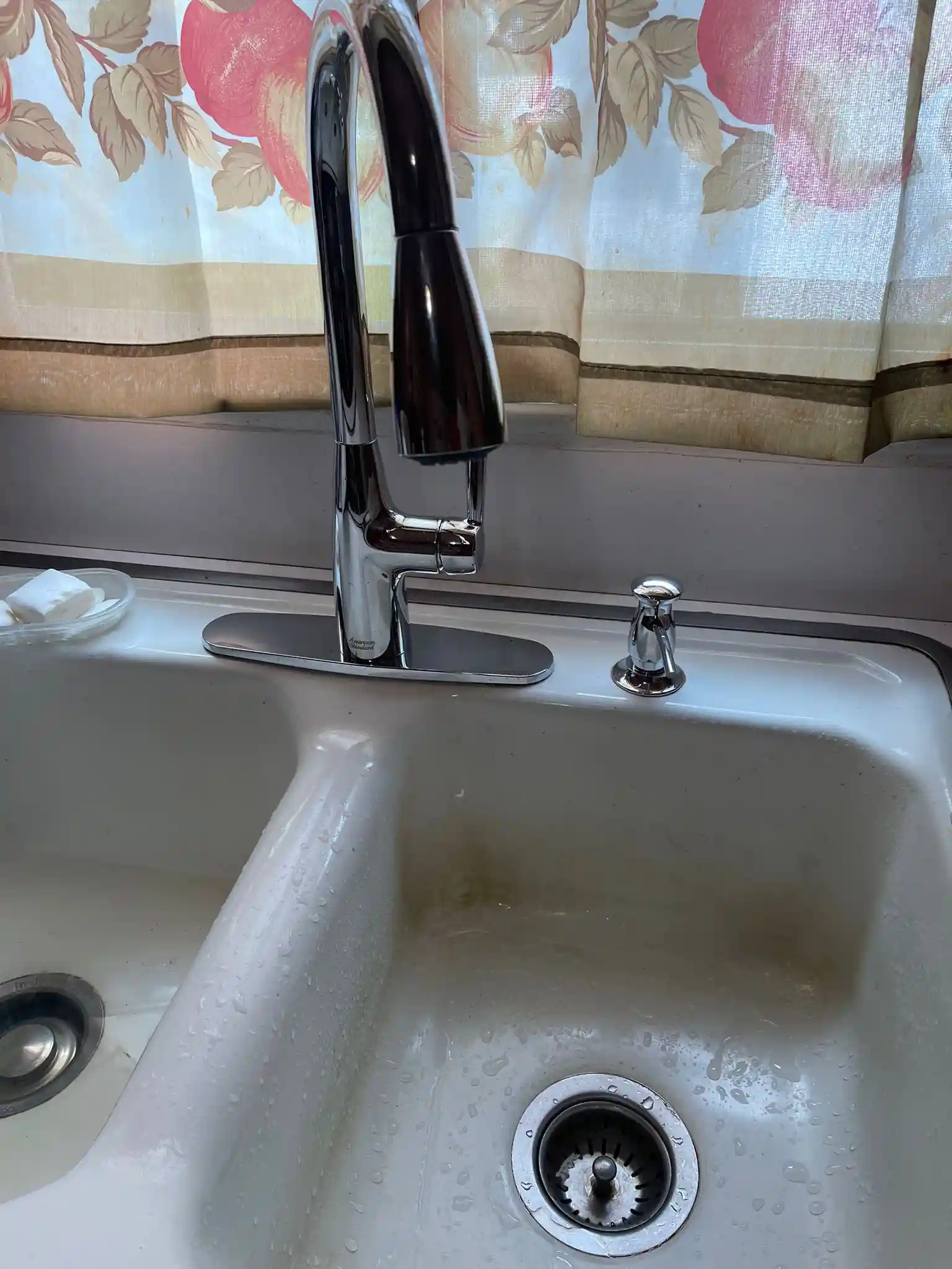 A modern chrome kitchen faucet and white double-basin sink, fixed by our team during an emergency faucet and sink repair.