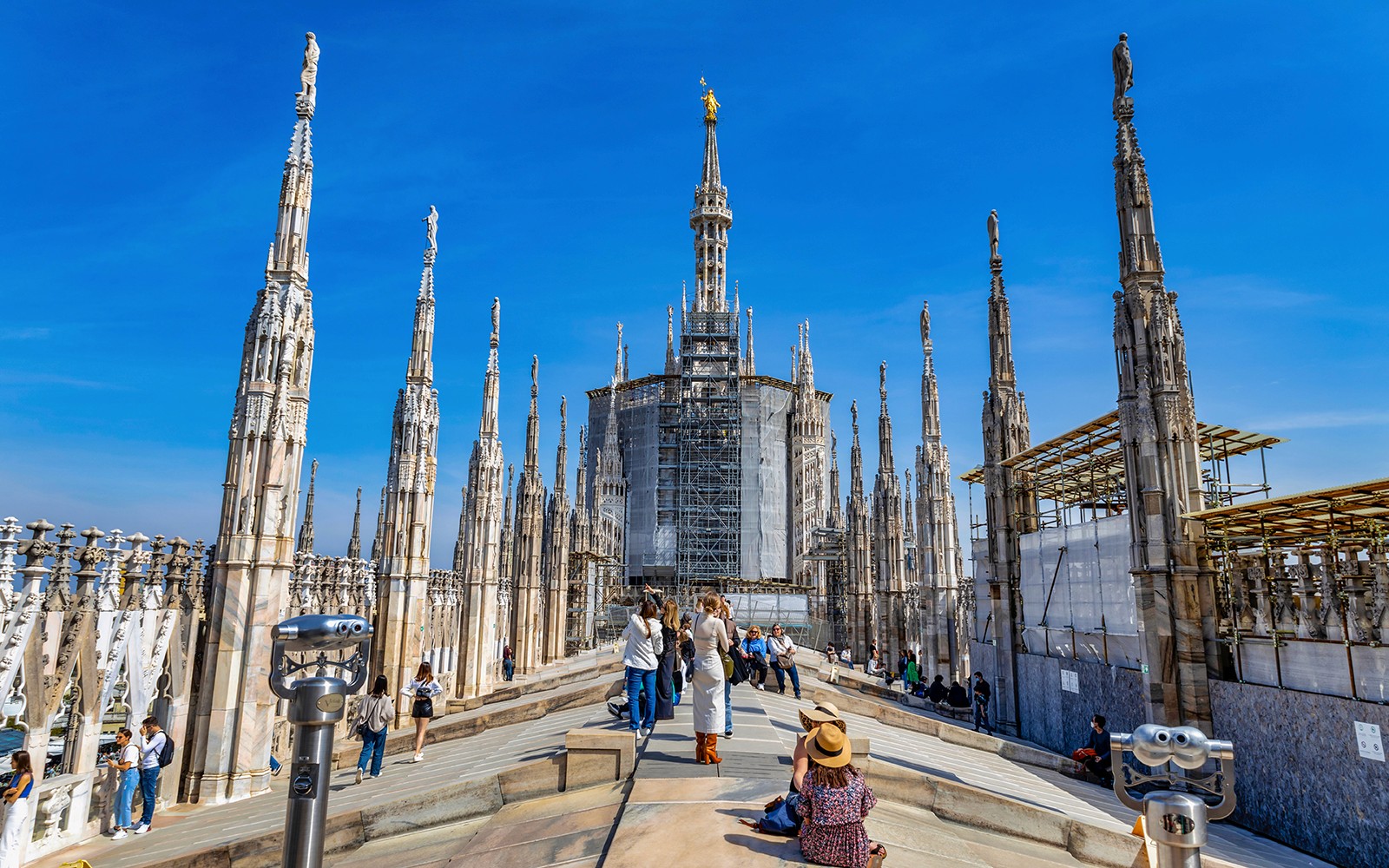 Turistas explorando la azotea del Duomo de Milán con las agujas a la vista.