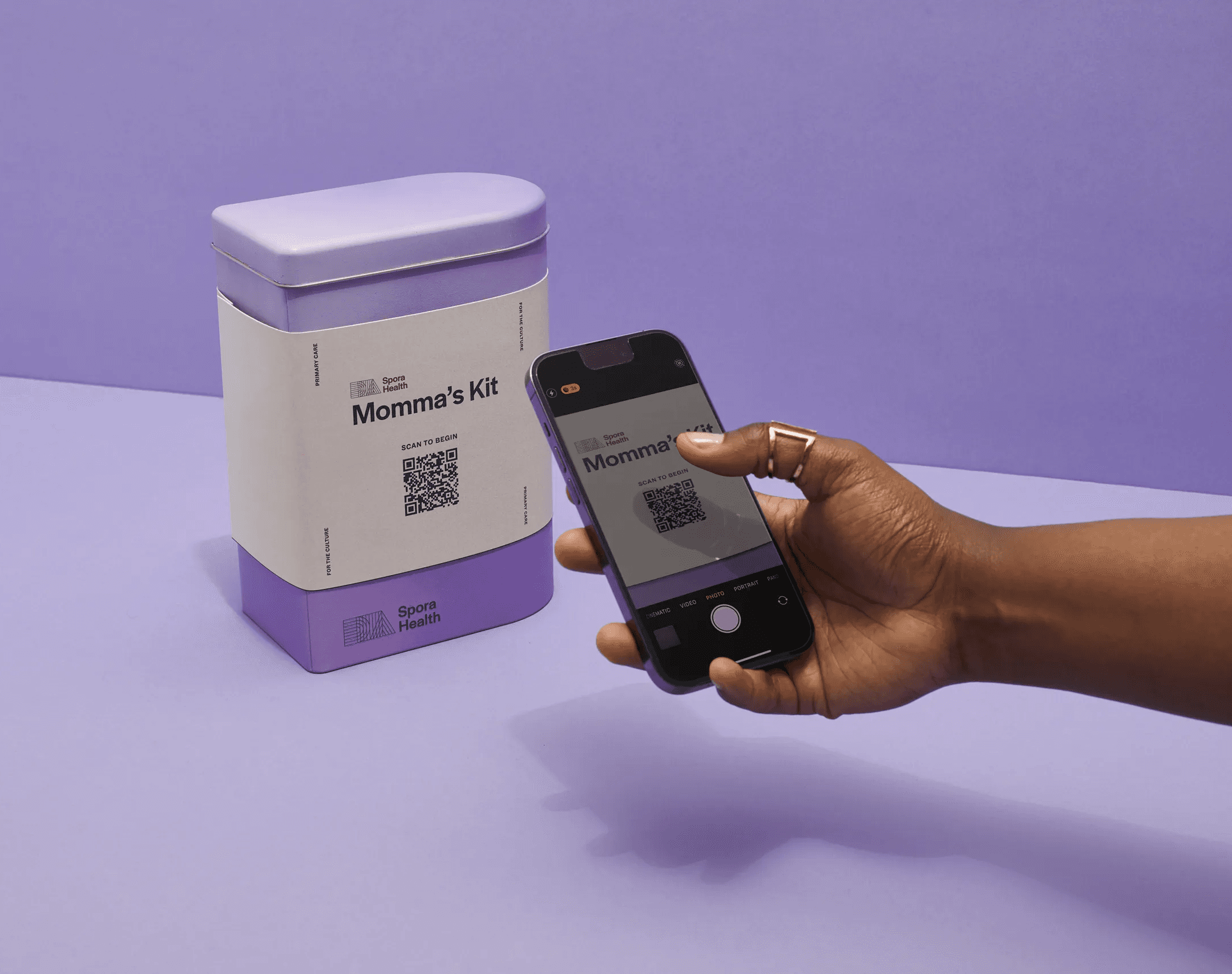 Hand holding a pulse oximeter beside the Spora Health Momma’s Kit container