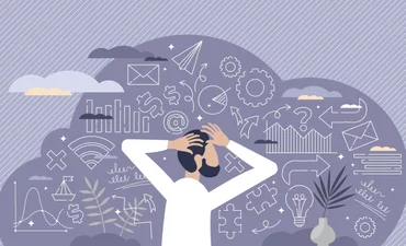 A dog sits on the grass, silhouetted against a beautiful sunset in the background.