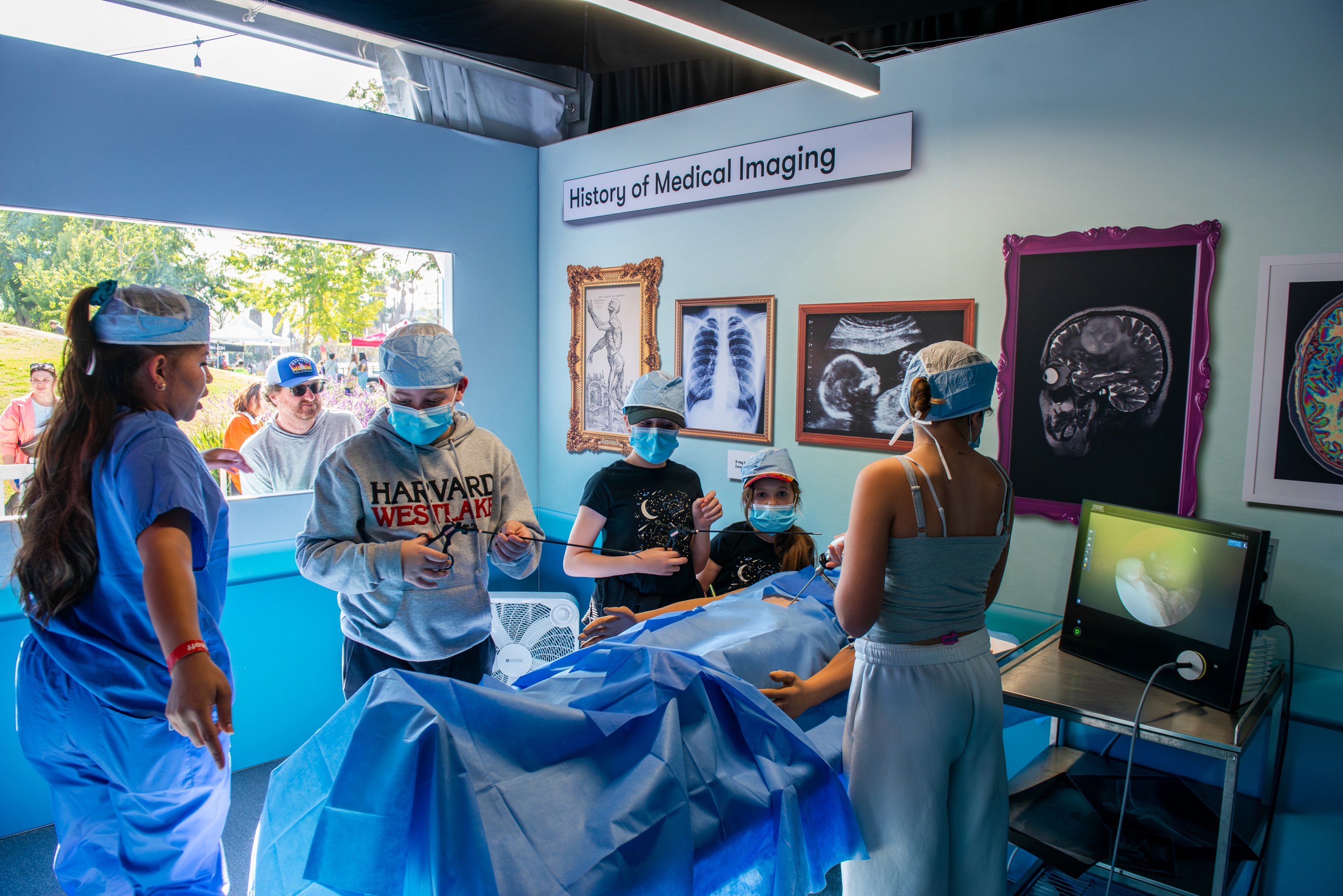 A volunteer assists a child with a science experiment in an interactive learning zone.