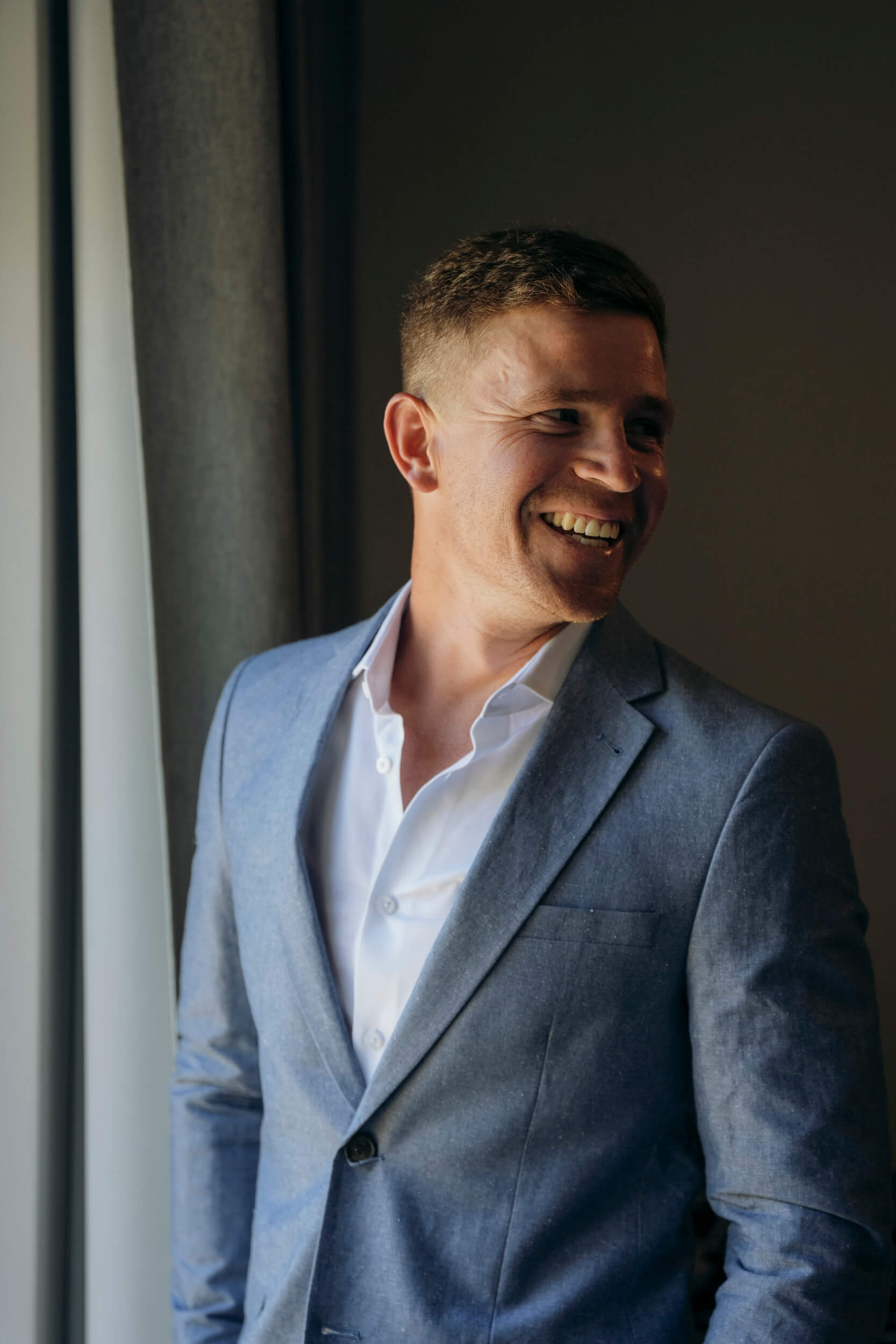 Groom looking back and smiling during relaxed wedding morning moment