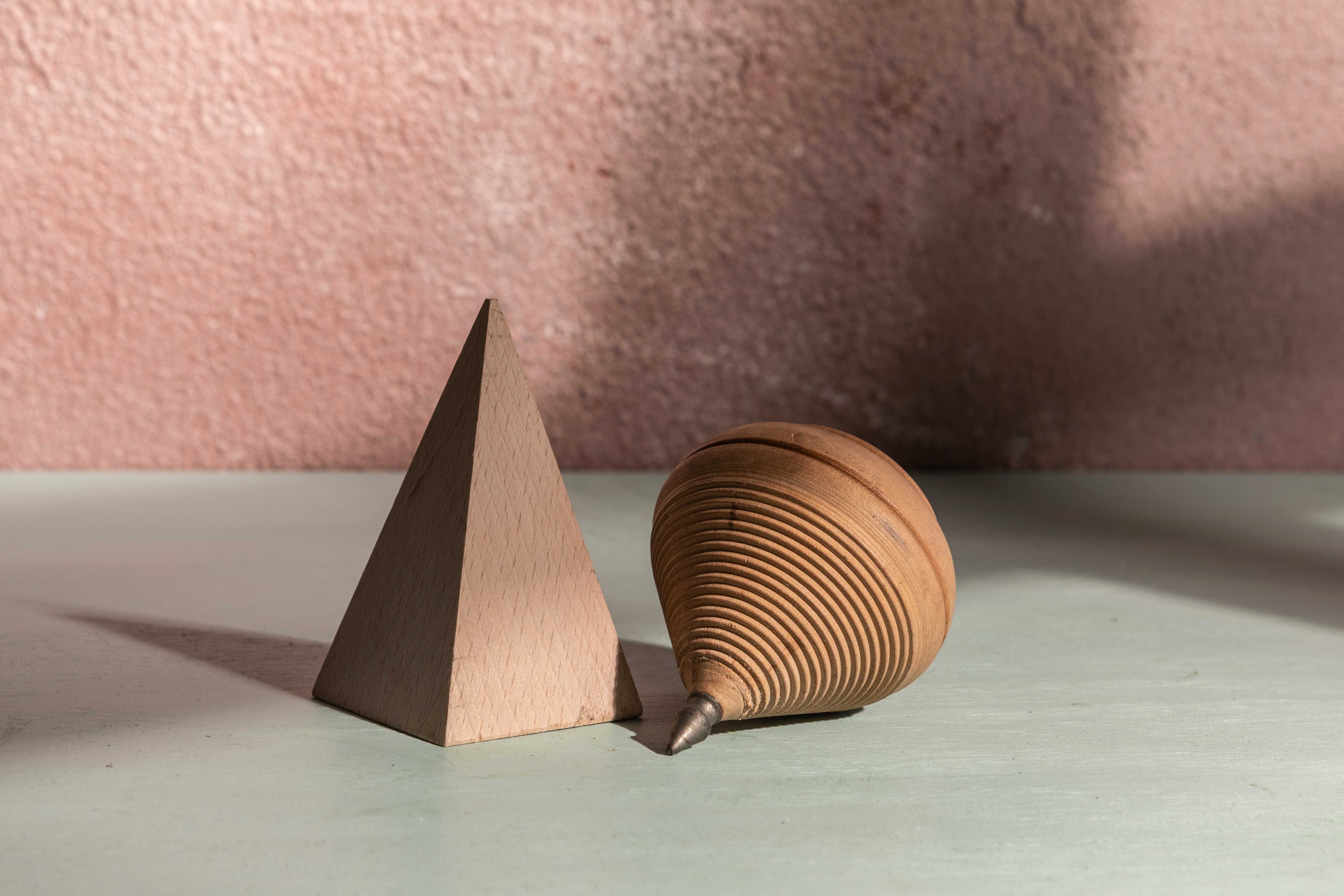 A pyramid and a top are pictured together.