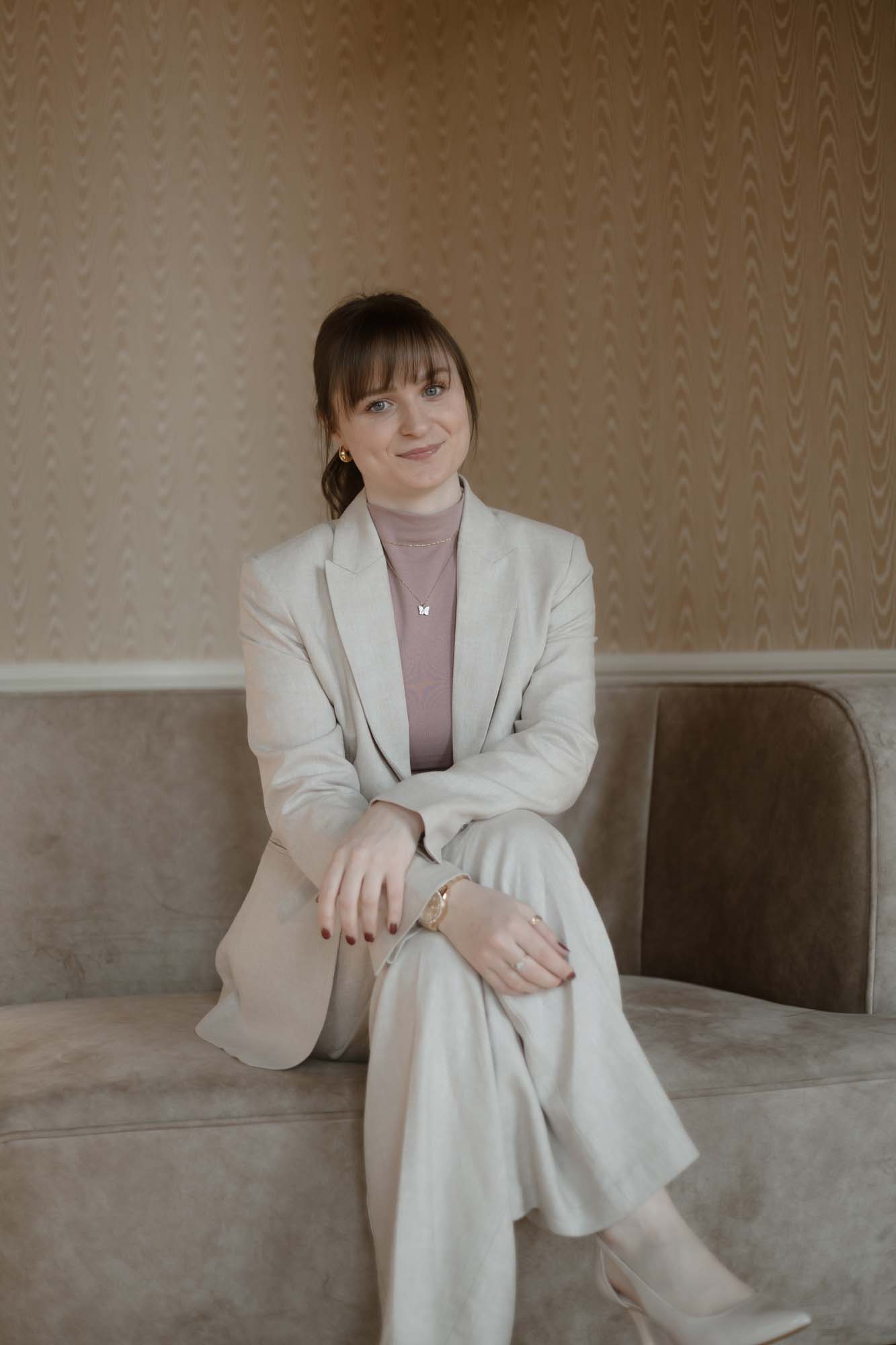 Planerin Emily sitzt auf einer Couch und schaut lächelnd in die Kamera.