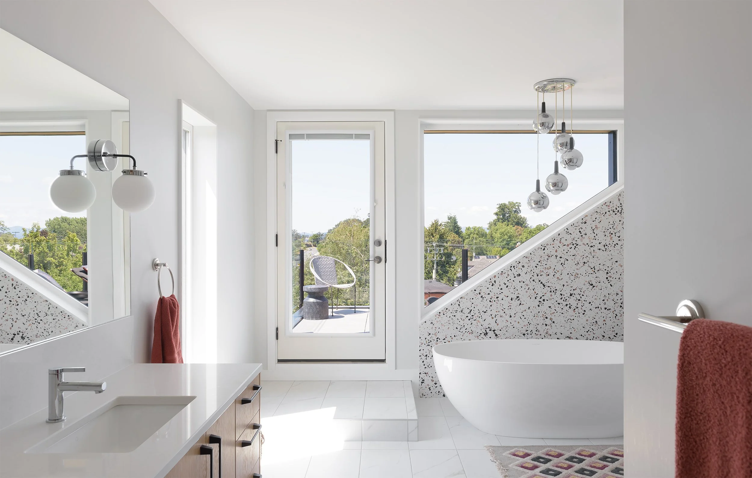 Modern indoor space with large glass doors, lush greenery, and a cozy seating area visible beyond.